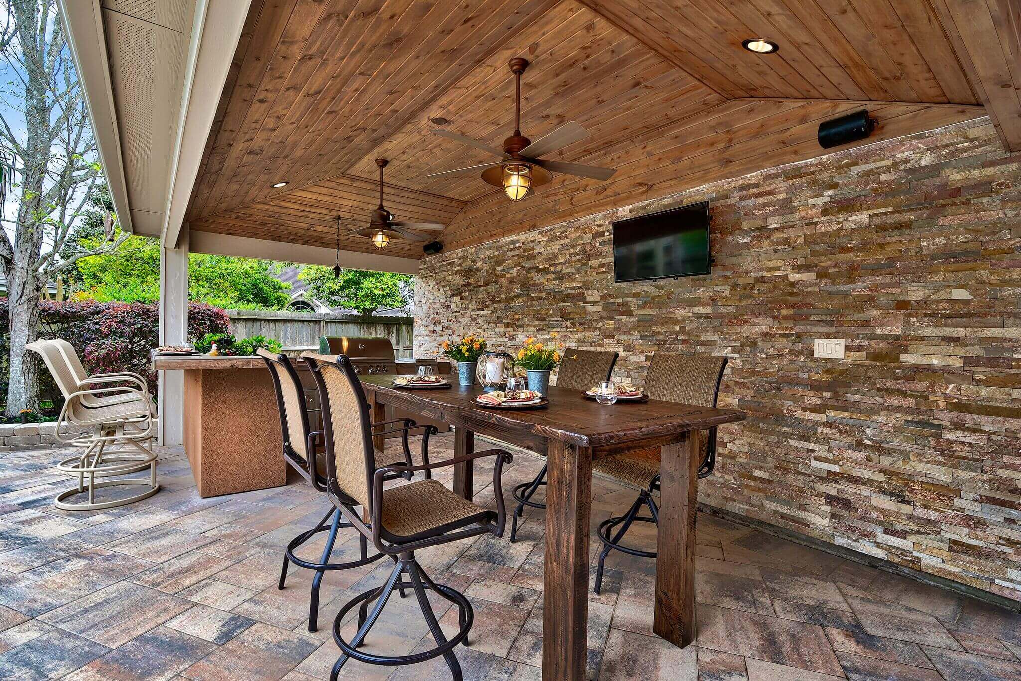 Outdoor kitchen and seating area under a patio cover with tv mount