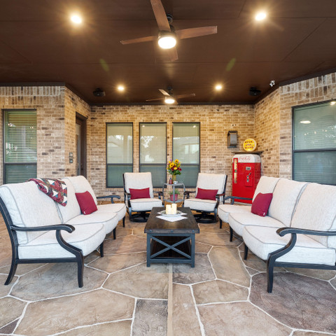 Backyard seating area underneath covered patio with carvestone overlay