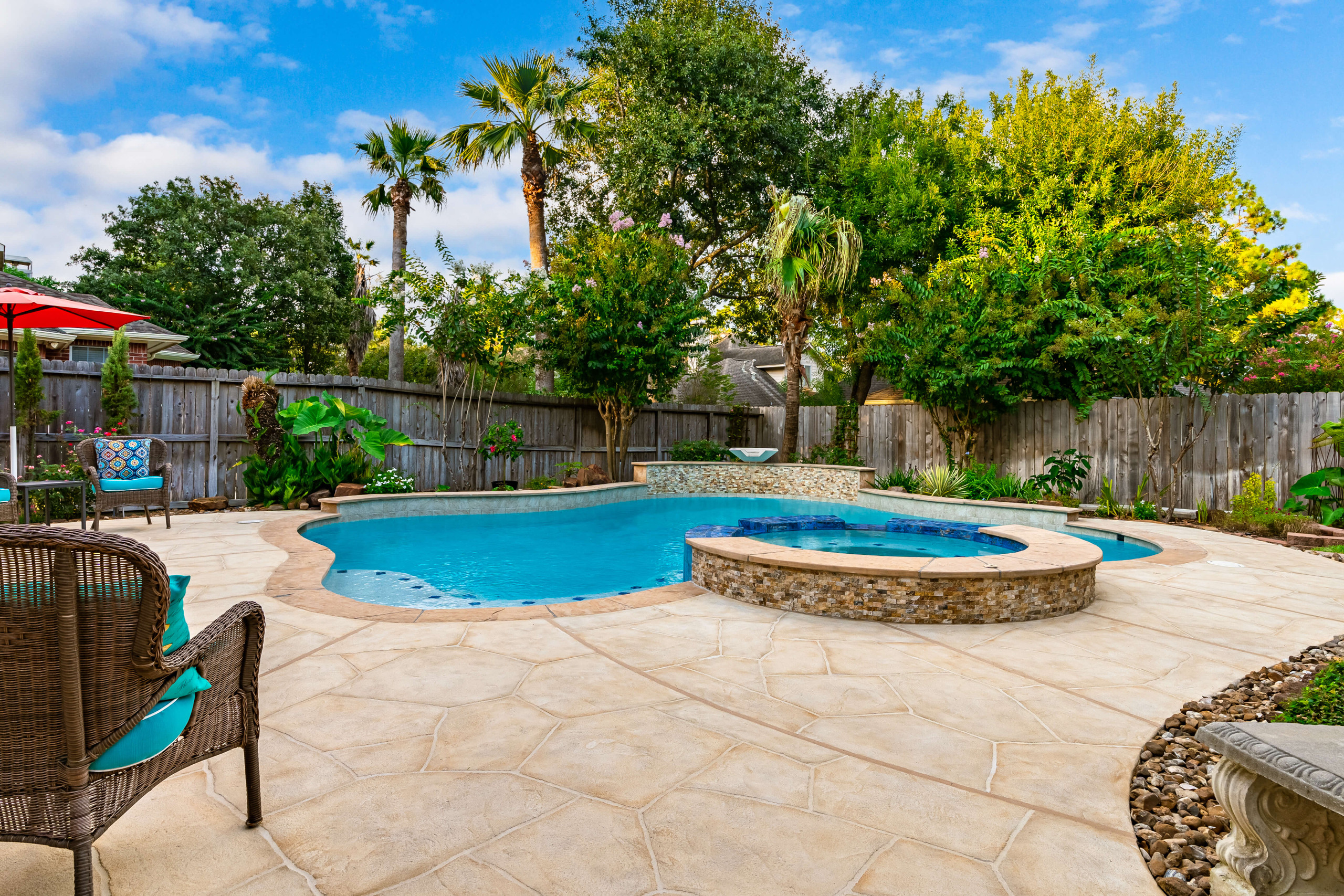 Freeform pool and carvestone pool deck backyard design