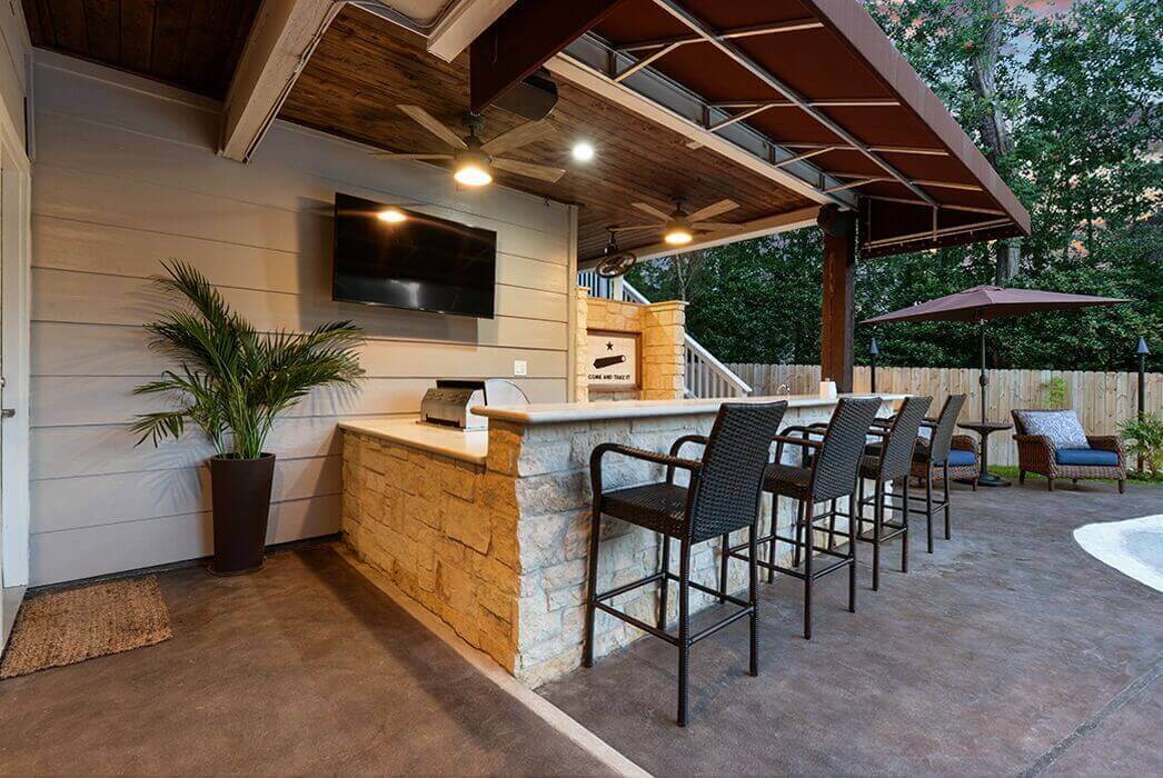 Backyard kitchen and bar stools underneath a covered patio