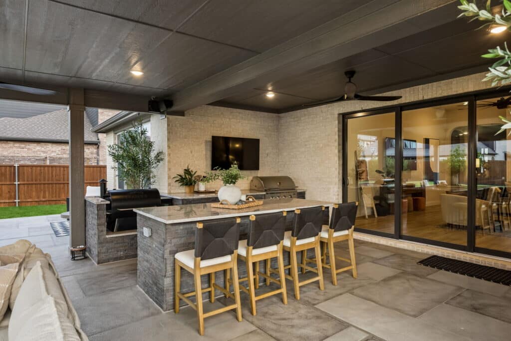 Covered outdoor kitchen with stone island and bar seating