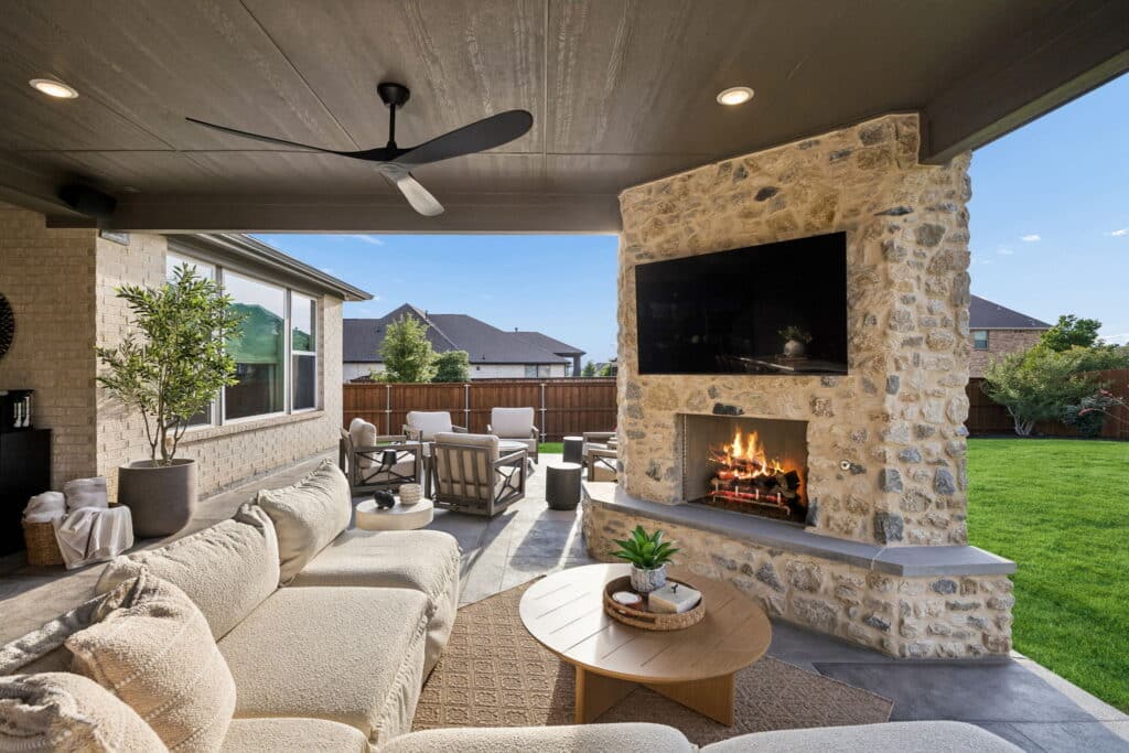 Covered patio with stone fireplace, TV, and outdoor lounge seating