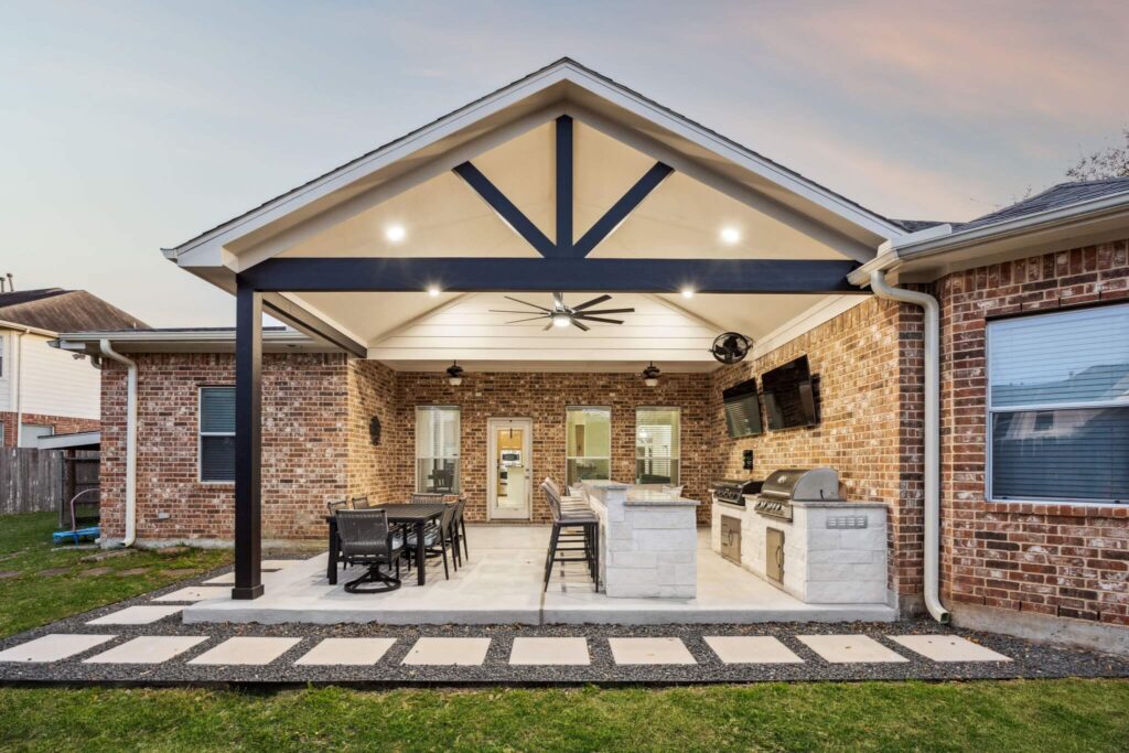 Covered outdoor kitchen with stone island and seating area