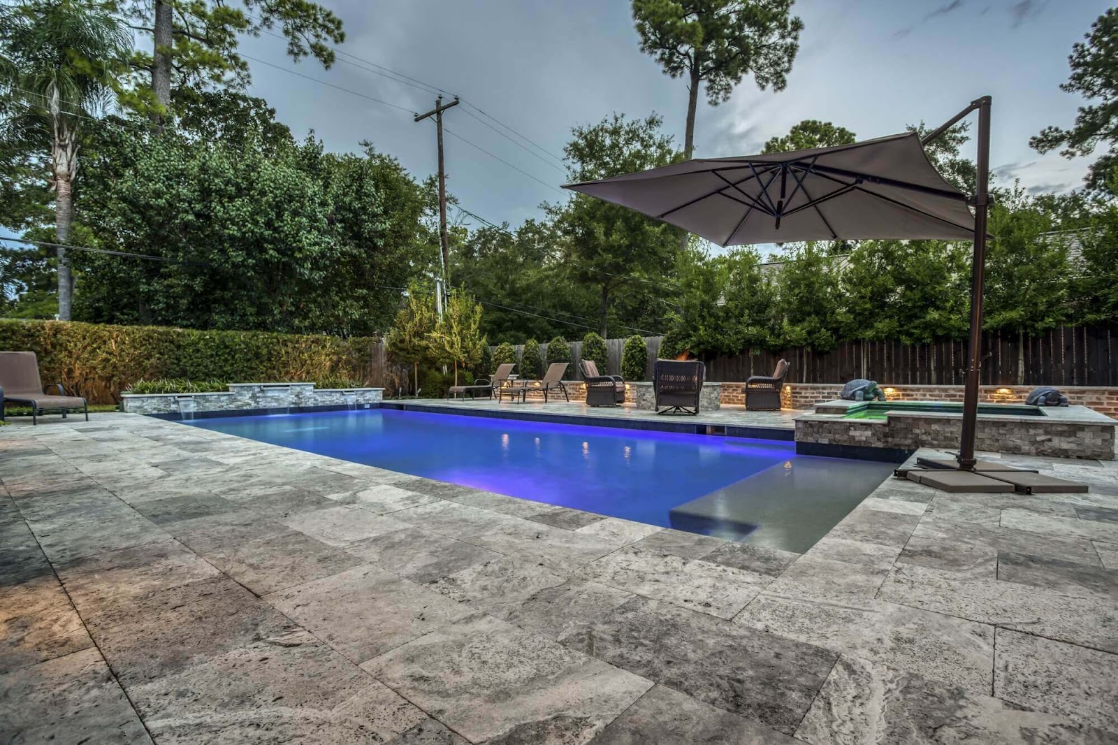 gray travertine natural stone pool decking with inground pool