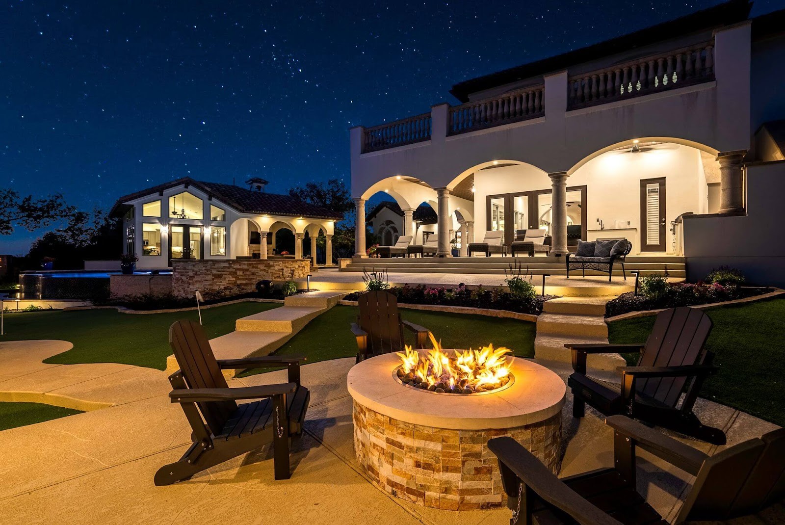 luxury backyard outdoor living design with custom fire pit, patio cover, putting green and swimming pool