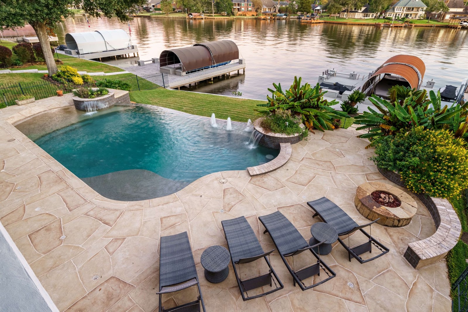 riverside backyard living idea with infinity pool, landscape features and carvestone pool deck