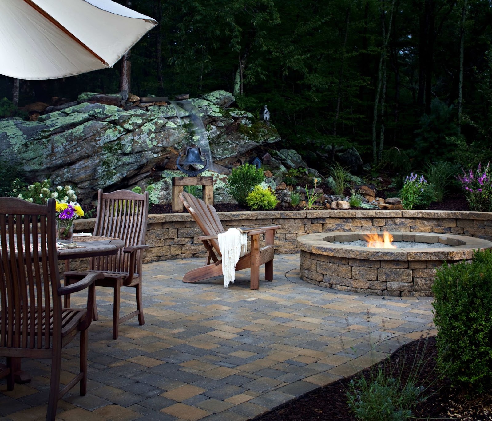 woodside outdoor patio design with flagstone pavers, custom fire pit and natural stone feature