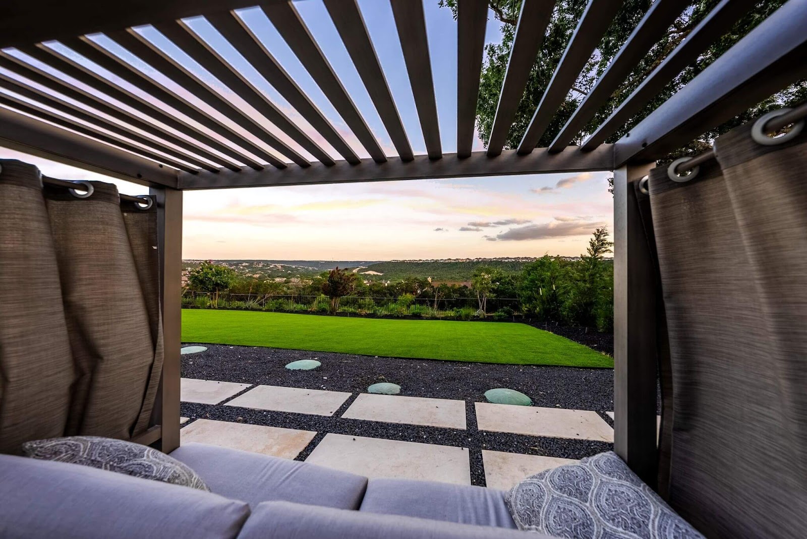 scenic view from TX covered pergola with cozy outdoor seating and privacy curtains