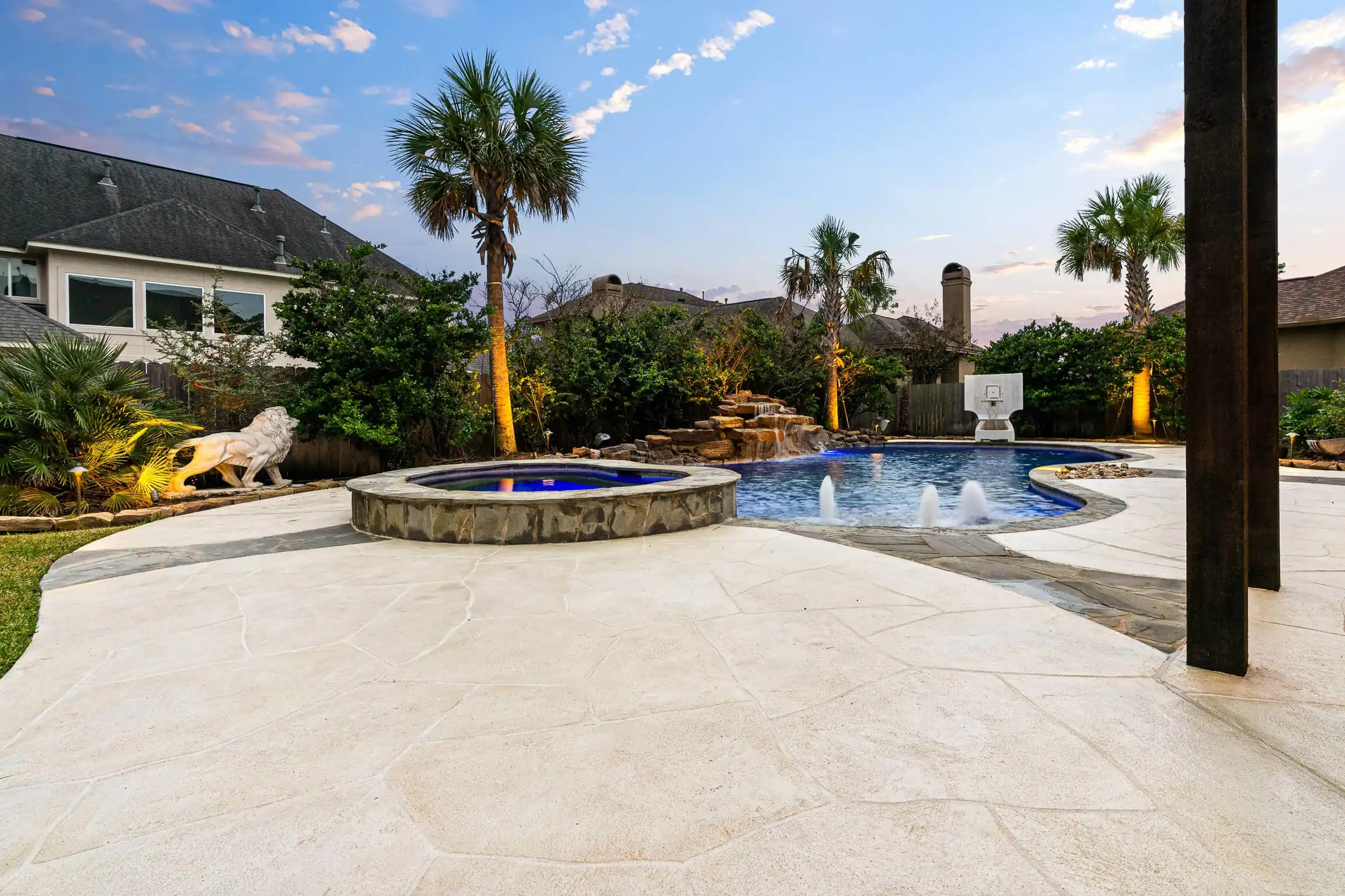 custom waterfall, elevated spa and gorgeous Carvestone overlay on remodeled pool deck and patio in Spring, TX