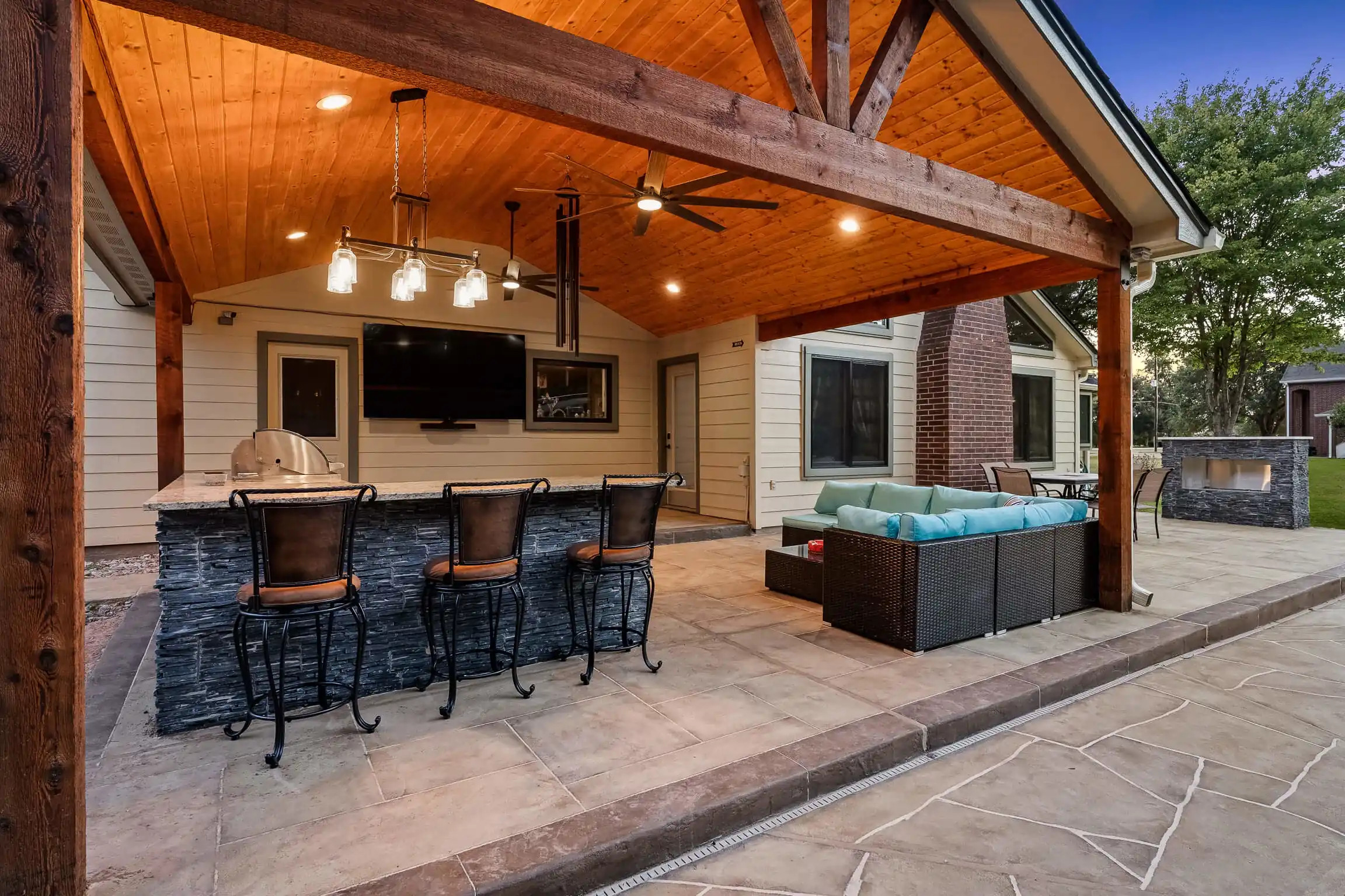 texas patio with gable roof structure, custom bar island and grill, outdoor fireplace and seating