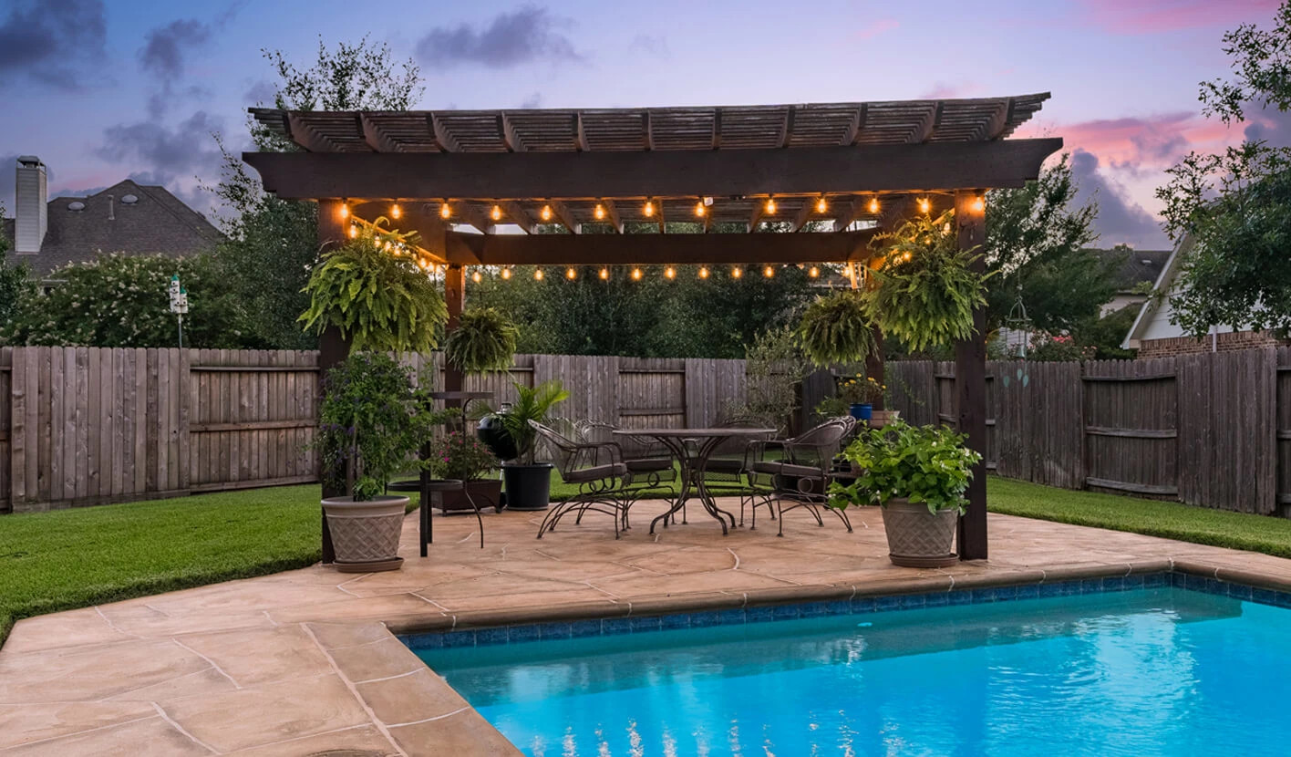 louvered pergola on pool deck next to inground pool in austin tx backyard