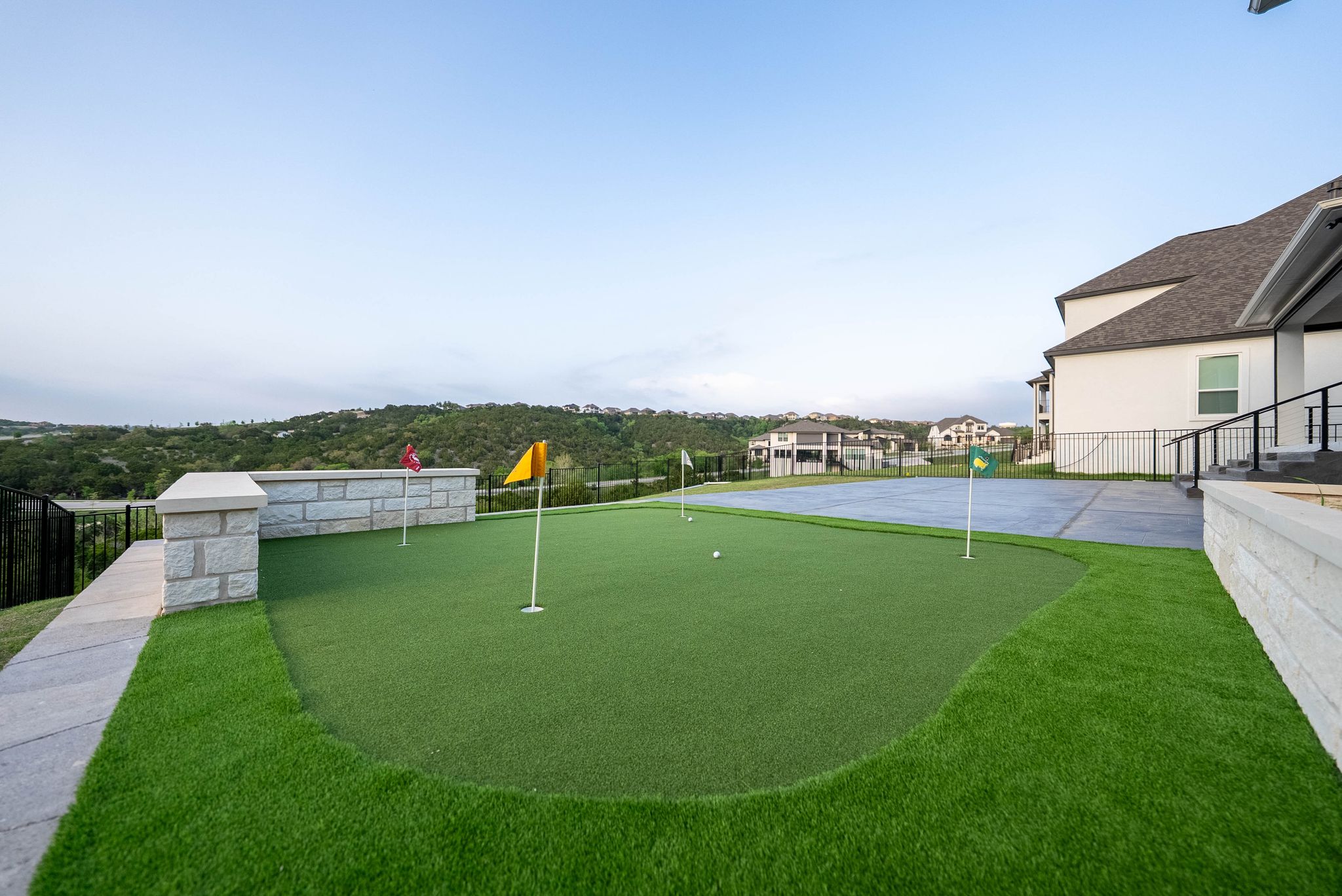Artificial turf putting green beside luxury backyard patio area